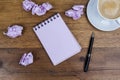 Notebook with pen aside coffee crumpled paper on wooden table