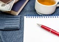 Notebook, pen, books, dollars and a cup of tea on a blue sweater Royalty Free Stock Photo