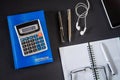 Notebook with pen, calculator and smartphone with headphones on black desktop. Accounting concept Royalty Free Stock Photo