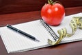 Notebook with pen, centimeter and cherry tomato on a wood background Royalty Free Stock Photo