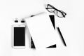 Notebook, pen, eye glasses, mobile phone, white sheet of paper, plant on a white background. Flat lay, top view, copy space. Royalty Free Stock Photo