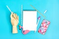 Notebook, pen, flamingo figure, smartphone, wooden hand hold drinking paper straws on blue background Royalty Free Stock Photo