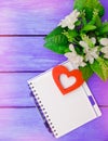 spring, notebook with pen, flowers, on a purple wooden background Royalty Free Stock Photo