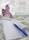 A notebook with a pen lying on his feet in striped socks