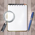 Notebook with pen and magnifier on a wooden board