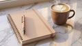 Notebook and pen next to a steaming coffee with heart latte art on a marble surface in warm sunlight Royalty Free Stock Photo
