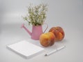 Notebook and pen, peaches and flowers in a watering can