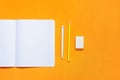 Notebook, pen, pencil and eraser on an orange wooden background. Top view Royalty Free Stock Photo