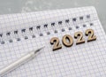 Notebook and pen on the table. Wooden numbers date 2022. A blank sheet of paper and a ballpoint pen Royalty Free Stock Photo