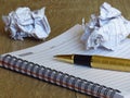 A notebook, a pen and two smashed paper sheet balls on dark wood background. Royalty Free Stock Photo