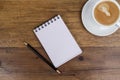 Notebook with pencil aside and coffee on wooden table