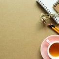 Notebook, pencil, dry flower, tea cup on brown background Royalty Free Stock Photo