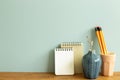 Notebook, pencil, eucalyptus on wooden desk. blue wall background Royalty Free Stock Photo