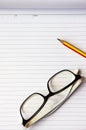 Notebook, pencil and eye glasses on wood background