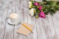 Notebook with a pencil next to coffee and peonies flowers on wooden background. Royalty Free Stock Photo