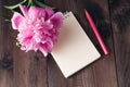 Notebook with a pencil and peonies flowers on the wooden background Royalty Free Stock Photo
