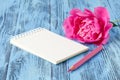 Notebook with a pencil and peonies flowers on the wooden background Royalty Free Stock Photo