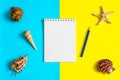 Notebook, pencil with seashells and sea stars on blue and yellow paper background. Mock up, flat lay, copy space, top view. Summer Royalty Free Stock Photo