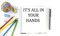 Notebook ,pencils,pen and rubber band with text IT`S ALL IN YOUR HANDS on the white background Royalty Free Stock Photo