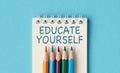 A notebook with pencils on it that says Educate Yourself. Royalty Free Stock Photo