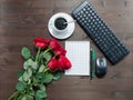 Notebook pens cup of coffee keyboard and red roses