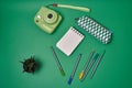 Notebook, pens and instax camera on green background Royalty Free Stock Photo