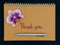 Notebook with phalaenopsis flower and pen. Text \'Thank you.\' Greeting card. Royalty Free Stock Photo