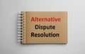 Notebook with phrase Alternative Dispute Resolution on white background, top view