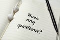 Notebook with phrase HAVE ANY QUESTIONS, earphones and pen