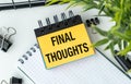 A notebook with a piece of paper that says Final Thoughts on it. The notebook is on a table with a pair of scissors and a plant. Royalty Free Stock Photo