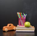 notebook pink stationery glass with multi-colored wooden pencils on the background of an empty black chalk board