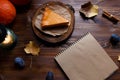 Notebook, pumpkin cheesecake, cooked at home, pumpkin, foliage, table lamp, vanilla on a wooden dark table Copy space Royalty Free Stock Photo