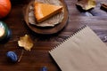 Notebook, pumpkin cheesecake, cooked at home, pumpkin, foliage, table lamp, vanilla on a wooden dark table Copy space Royalty Free Stock Photo