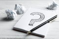 Notebook with question mark, pen and crumpled paper on wooden table, closeup Royalty Free Stock Photo