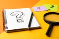 Notebook with question mark, pen and magnifier glass on color background Royalty Free Stock Photo