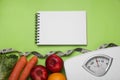 Notebook, scales, fresh fruits and vegetables on light green background, flat lay. Low glycemic index diet Royalty Free Stock Photo