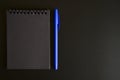 Notebook on a spring with black sheets and a blue pen on a black background. space for text. Royalty Free Stock Photo