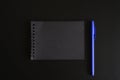 Notebook on a spring with black sheets and a blue pen on a black background. space for text. Royalty Free Stock Photo