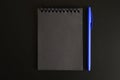 Notebook on a spring with black sheets and a blue pen on a black background. space for text. Royalty Free Stock Photo