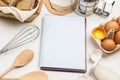 Notebook on springs. Two wooden spoons. Chicken eggs and chicken shells. Flour and sieve on paper. Royalty Free Stock Photo