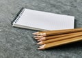 Notebook and stack of simple golden colored pencils on gray background