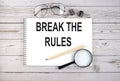 Notebook with text BREAK THE RULES on the wooden table with pen, magnifier and glasses Royalty Free Stock Photo