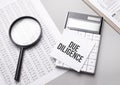 Notebook with text due diligence sheet of white paper for notes, calculator, magnifying glass. Business concept Royalty Free Stock Photo