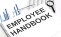 In the notebook, the text Employee handbook , next to magnifier and a pen, the background is graphics Royalty Free Stock Photo