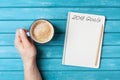 Notebook with text 2018 goals and cup of coffee on wooden desk top view. Planning and business concept. New year resolution.