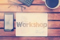 Notebook with text inside Workshop on table with coffee, mobile Royalty Free Stock Photo
