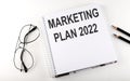 Notebook with text MARKETING PLAN 2022 on the white background Royalty Free Stock Photo