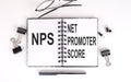 Notebook with text NPS NET PROMOTER SCORE on a table