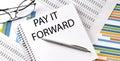 Notebook with text PAY IT FORWARD . Diagram and white background,Business concept Royalty Free Stock Photo