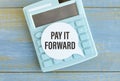 Text PAY IT FORWARD sheet of white paper for notes, calculator. Business concept Royalty Free Stock Photo